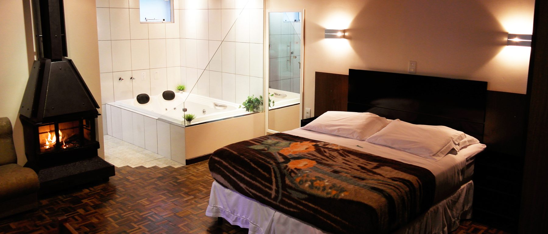Suíte com lareira acesa, cama e banheira de hidromassagem